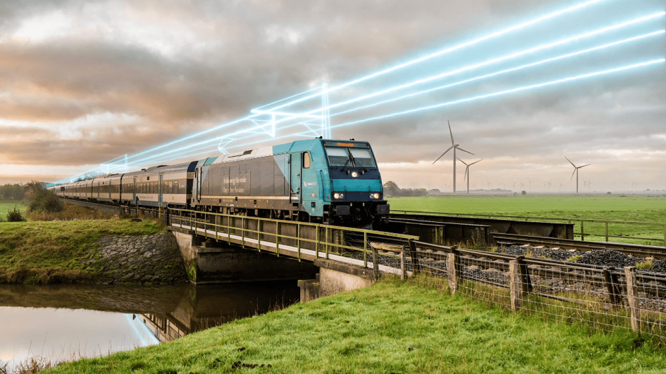 Marschbahn electrification -
A train crosses a bridge in a scenic rural area with wind turbines and glowing blue lines in the cloudy sky, symbolizing modern technology and sustainability.